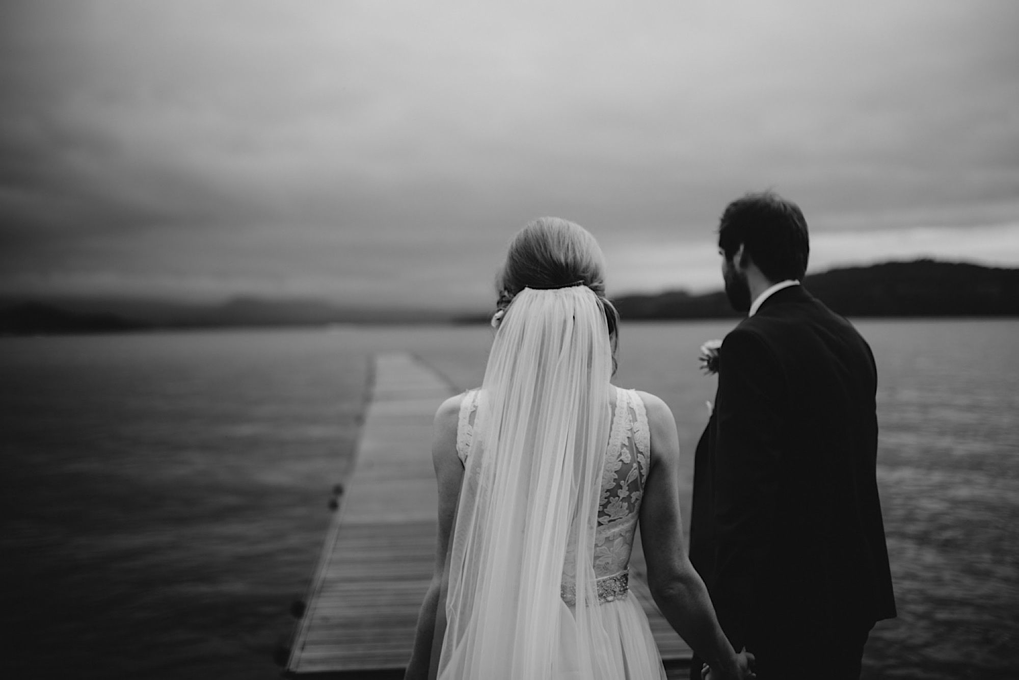 bride and groom on the banks of loch lomand with a dark and moody sky as the rain stops