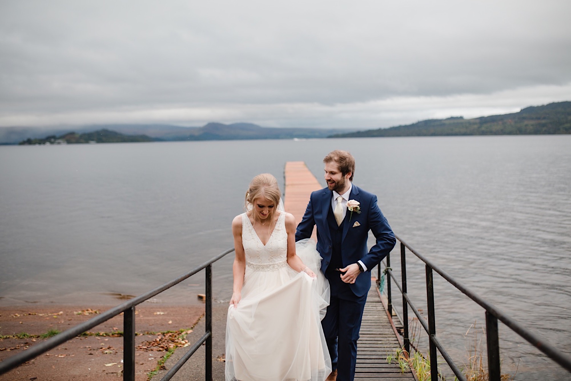 bride and groom on the banks of loch lomand with a dark and moody sky as the rain stops